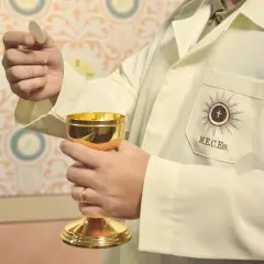 Dłoń trzymająca hostię i złoty kielich. Czy przeklinanie to grzech? To pytanie nie dotyczy tej świętej chwili.