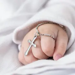 Dziecięca dłoń z krzyżykiem na nadgarstku. Zastanawiasz się, ile trwa msza z chrztem?