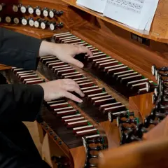 Dłonie organisty grają na klawiaturze. Zastanawiasz się, ile zarabia organista za mszę?