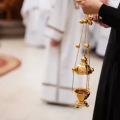 Złota kadzielnica w ręku osoby w czarnej szacie. Czy msza w środę popielcową jest obowiązkowa?