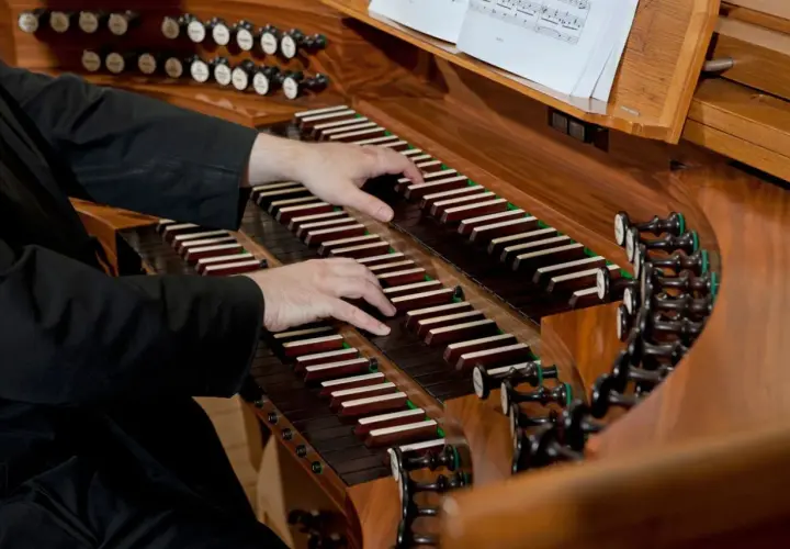 Dłonie organisty grają na klawiaturze. Zastanawiasz się, ile zarabia organista za mszę?