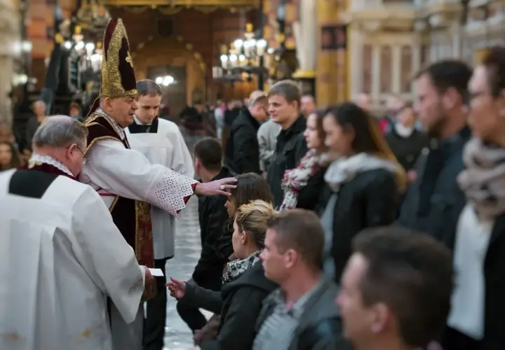 Biskup udziela sakramentu bierzmowania. Czy świadek do bierzmowania musi być pełnoletni? Wierni czekają w kościele.