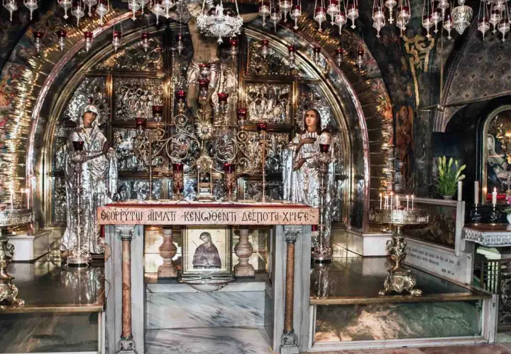 Wnętrze kaplicy Grobu Pańskiego, miejsca, gdzie umarł Jezus. Złote zdobienia, ikony i świece tworzą atmosferę świętości.