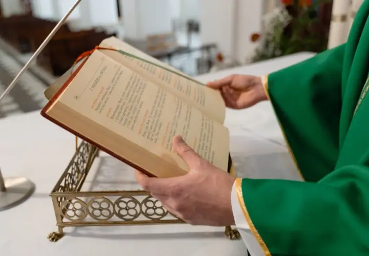 Kapłan w zielonej szacie czyta z księgi liturgicznej. Zastanawiasz się, ile trwa msza niedzielna?