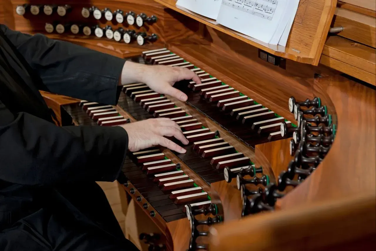 Dłonie organisty grają na klawiaturze. Zastanawiasz się, ile zarabia organista za mszę?