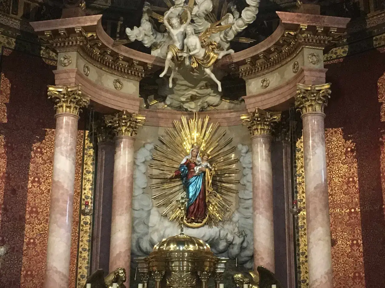 Ołtarz z figurą Matki Boskiej z Dzieciątkiem, otoczoną złotymi promieniami. Nad nią aniołowie. Czy józef współżył z maryją? Pytanie to nie znajduje odpowiedzi w tej scenie.