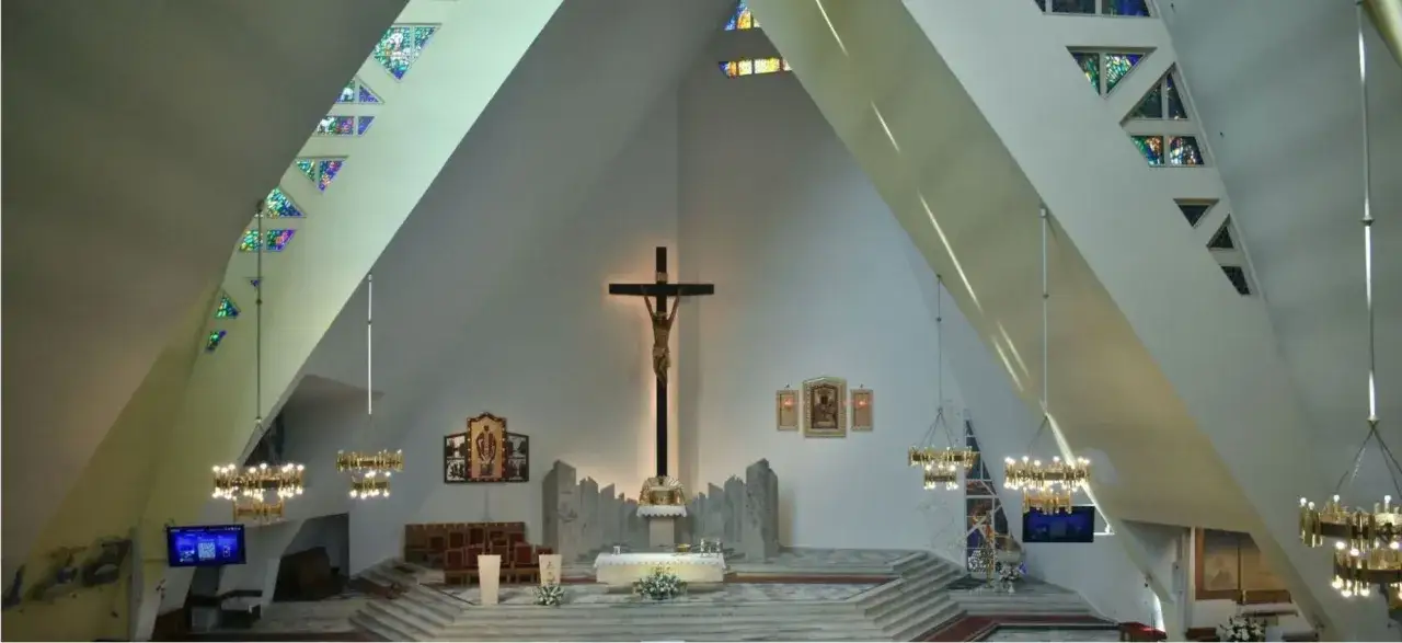 Wnętrze kościoła z ołtarzem, krzyżem i witrażami. Dowiedz się, jak zamówić mszę świętą w Częstochowie.