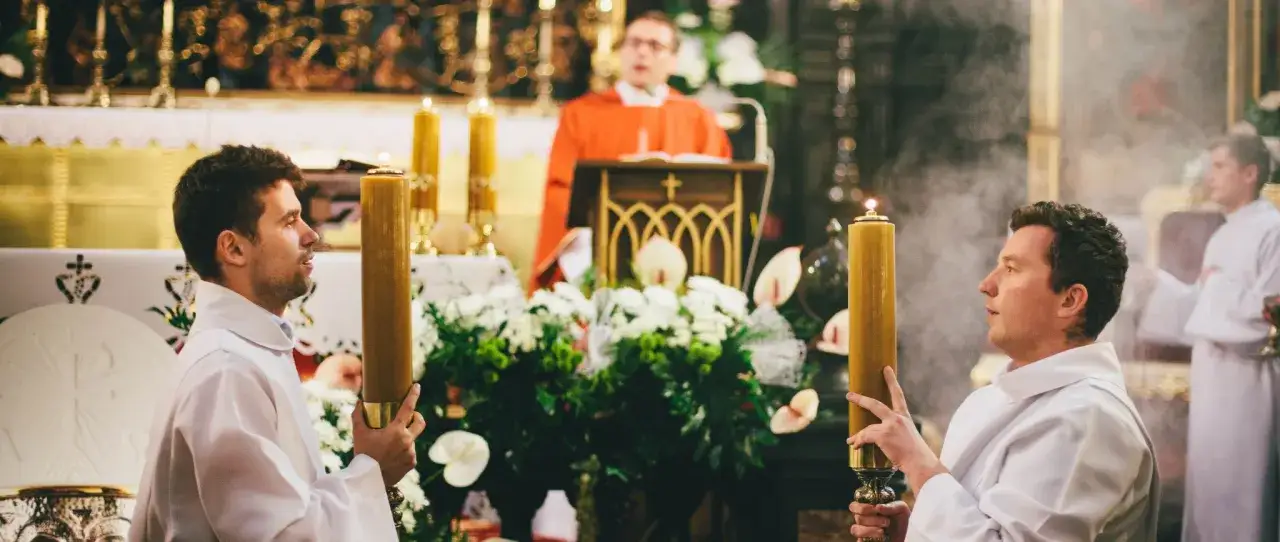 Dwóch ministrantów z zapalonymi świecami podczas mszy. Zastanawiasz się, ile trwa msza święta w tygodniu?