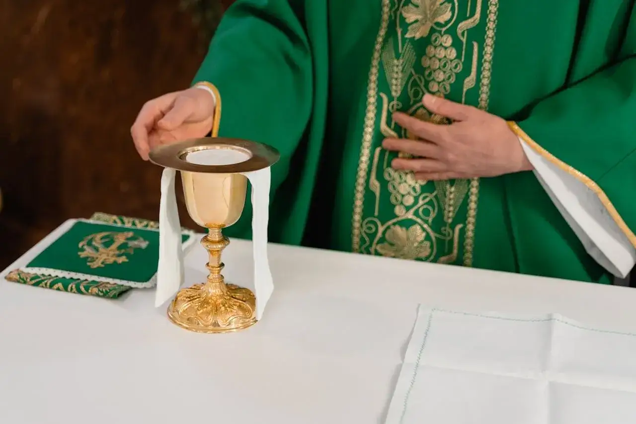 Kapłan w zielonej szacie z haftem winorośli przygotowuje się do mszy. Złoty kielich z hostią i białą welonem stoi na ołtarzu. Czas mszy za zmarłego jest różny.